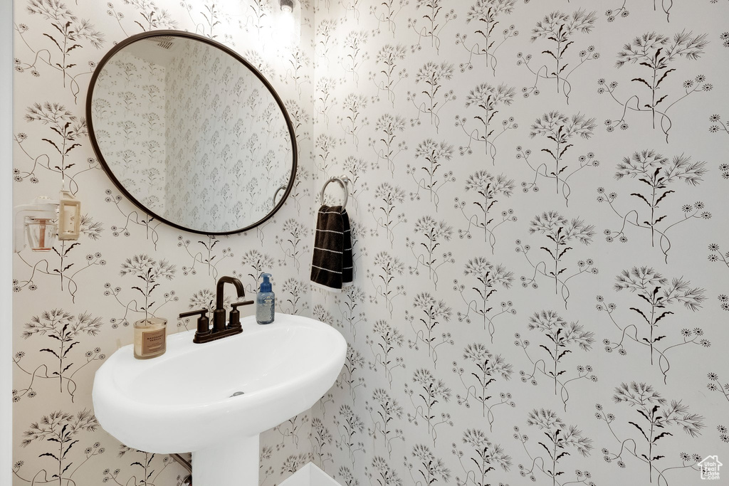 Bathroom featuring wallpapered walls and a sink