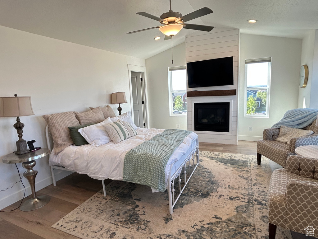 Bedroom featuring multiple windows, baseboards, vaulted ceiling, wood finished floors, and recessed lighting