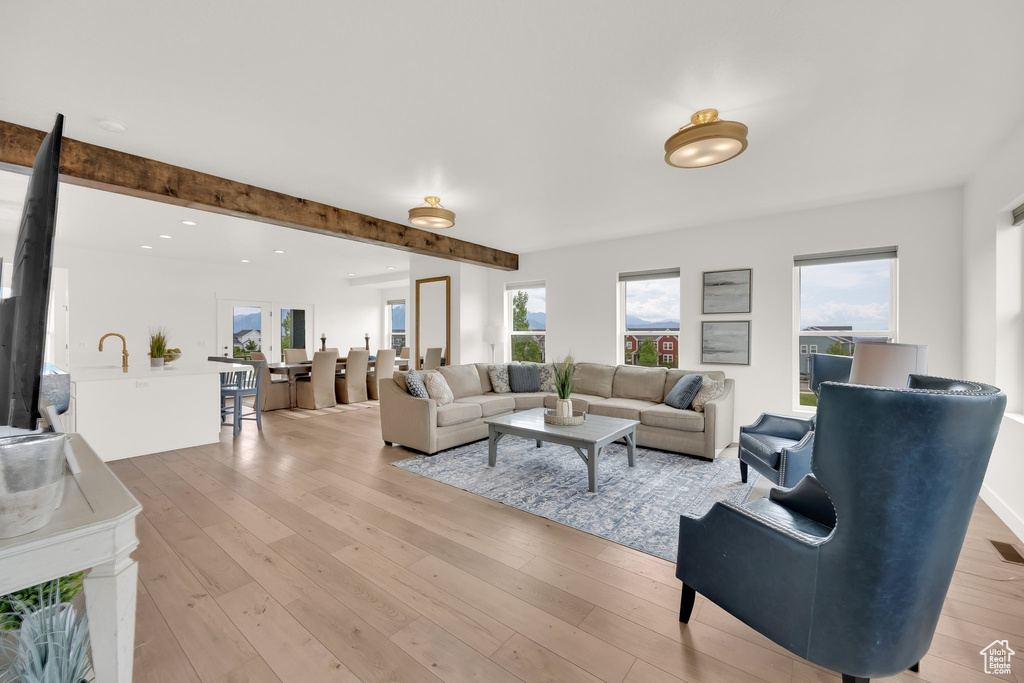 Living room with light wood-style flooring, beamed ceiling, and recessed lighting