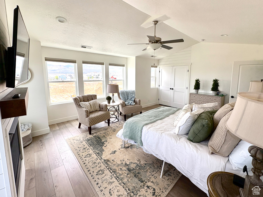 Bedroom featuring baseboards, lofted ceiling, light wood-type flooring, and ceiling fan