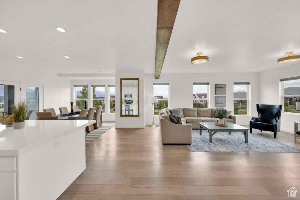 Living area with healthy amount of natural light, light wood-type flooring, recessed lighting, beamed ceiling, and baseboards