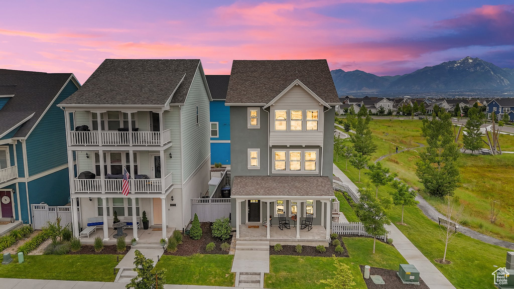 View of front of property with a patio area, a mountain view, and a shingled roof