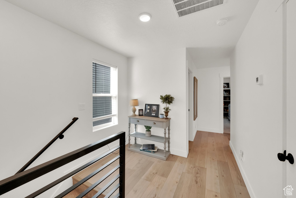 Hallway featuring an upstairs landing, light wood finished floors, and baseboards