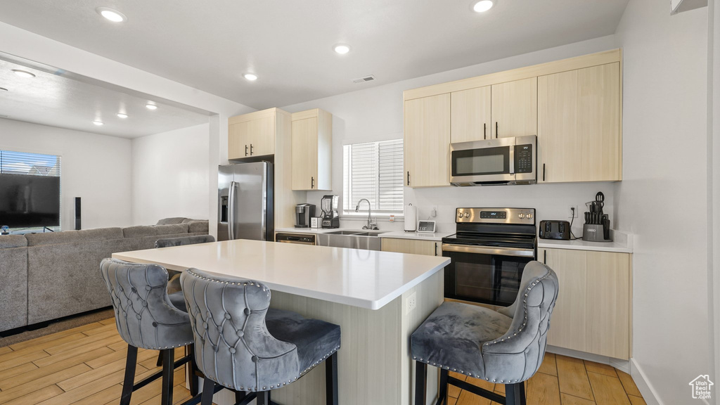 Kitchen featuring appliances with stainless steel finishes, a kitchen breakfast bar, a sink, open floor plan, and recessed lighting