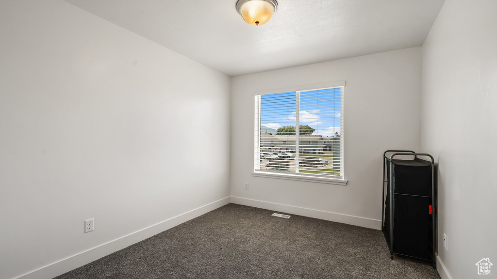 Empty room with baseboards and dark carpet