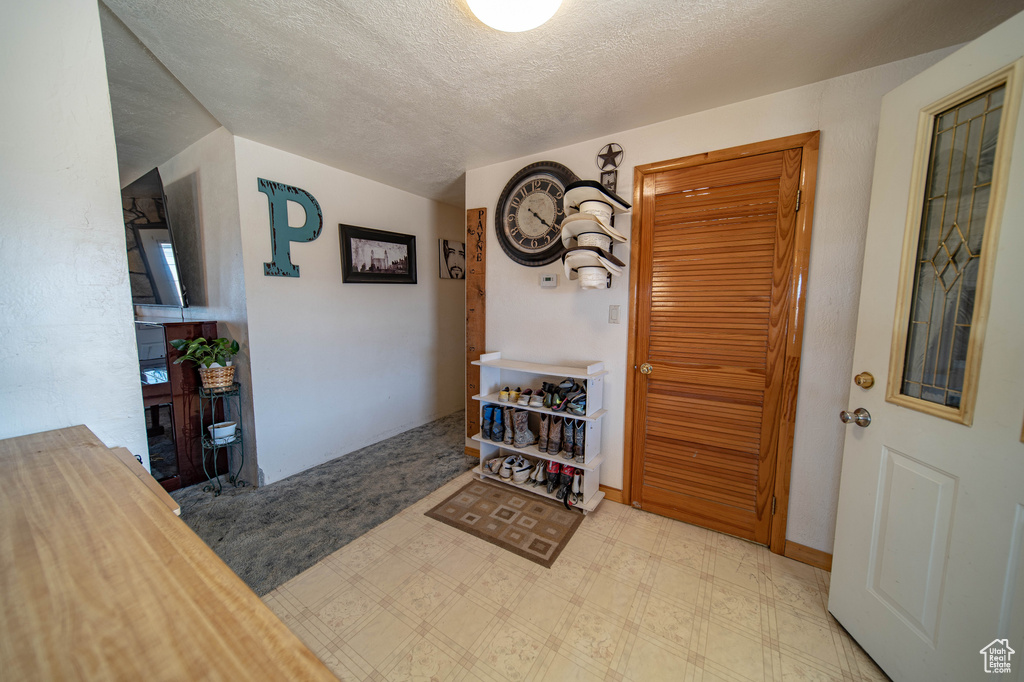 Entrance foyer with a textured ceiling, tile patterned floors, and a fireplace