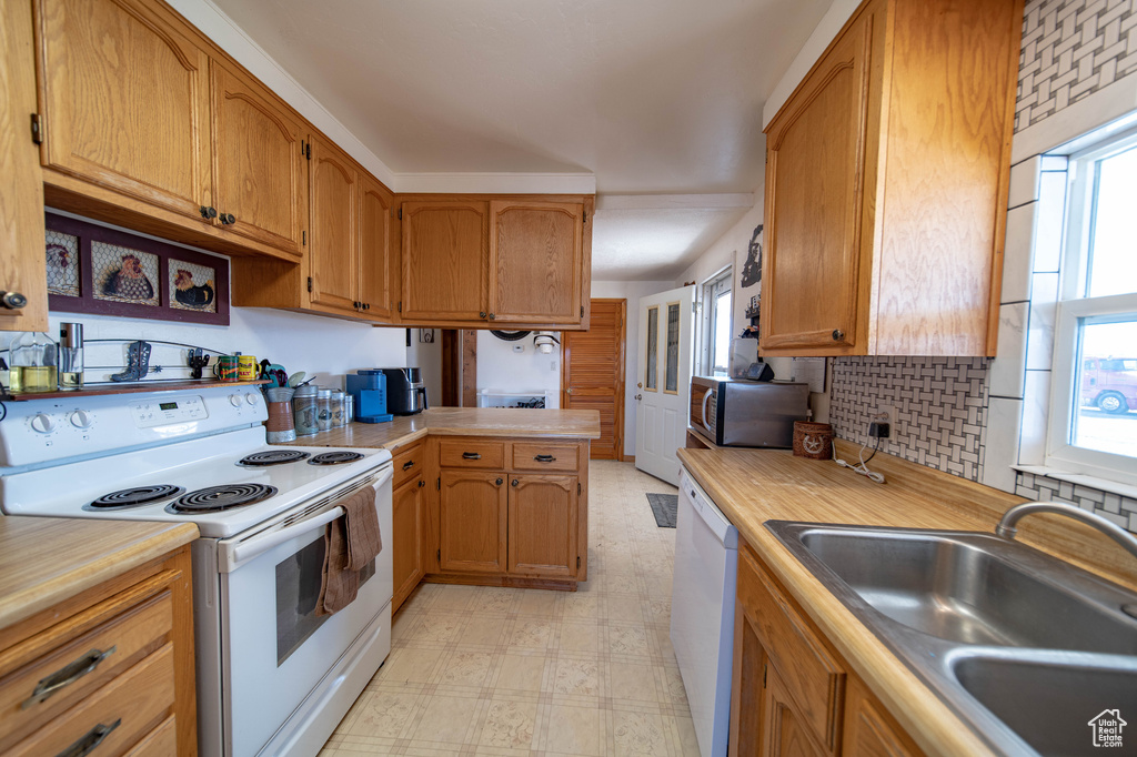 Kitchen with white appliances, a sink, light floors, and light countertops