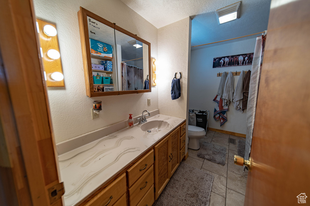 Full bath with toilet, vanity, a textured ceiling, a textured wall, and a shower with shower curtain