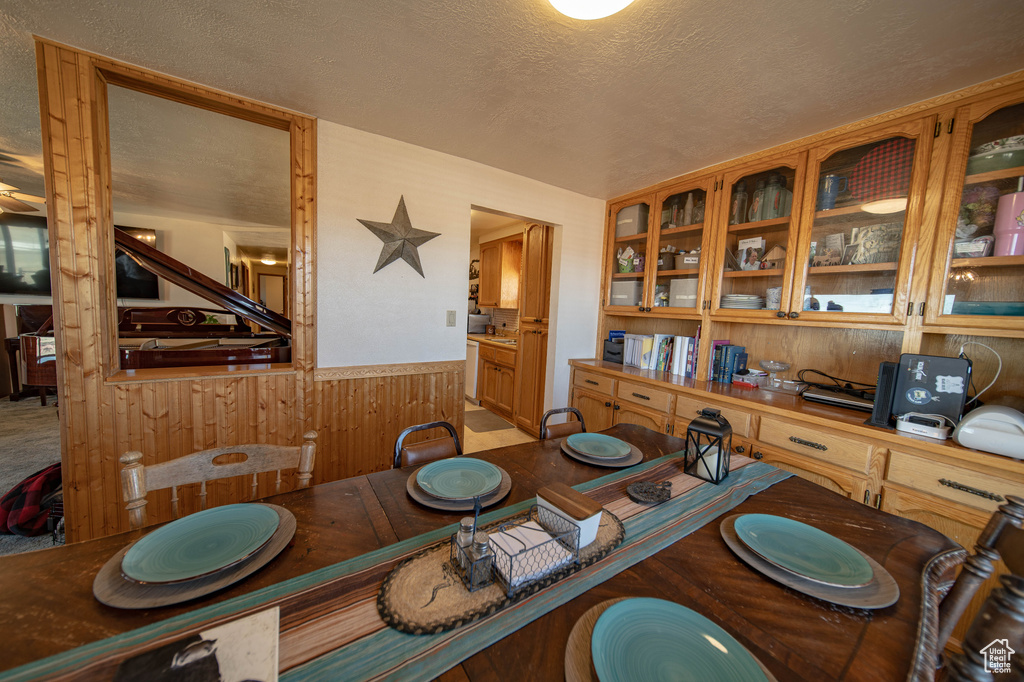Dining space with wooden walls, wainscoting, and a textured ceiling