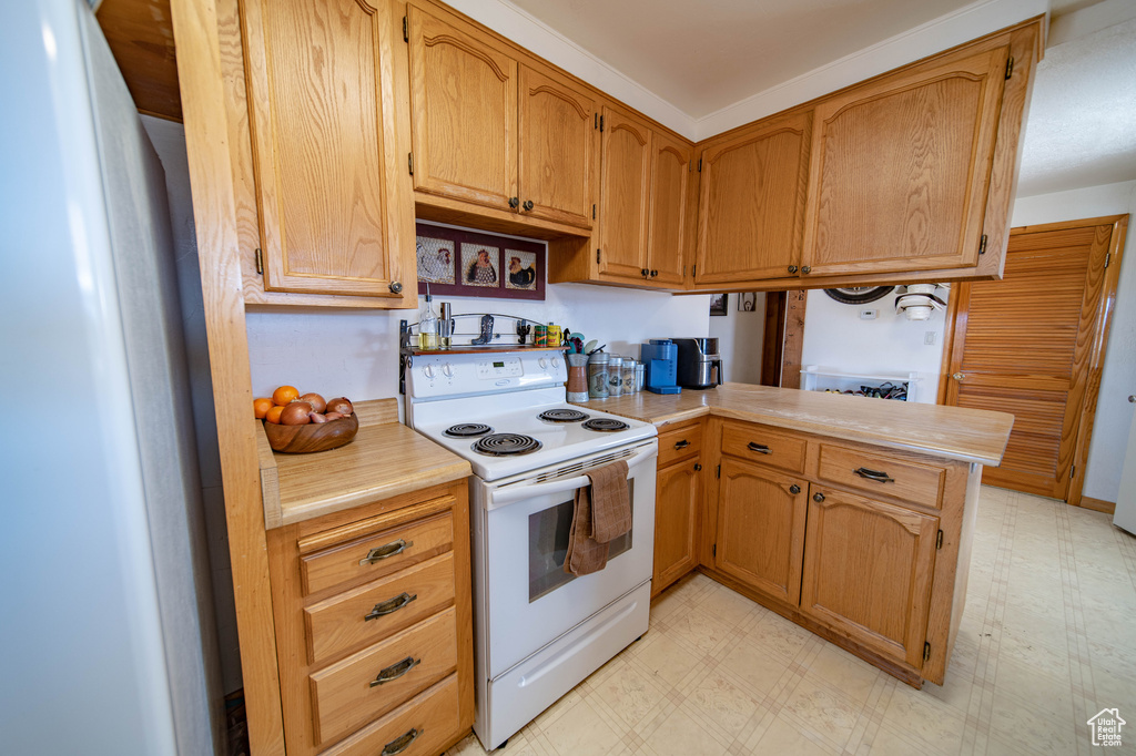 Kitchen with electric stove, light floors, and light countertops
