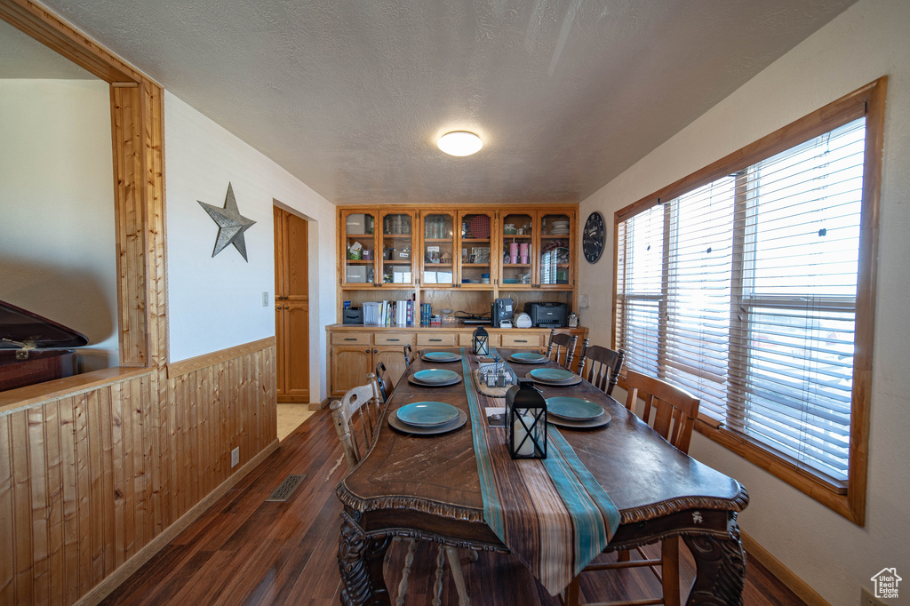 Dining space featuring a wainscoted wall, wood finished floors, and wood walls