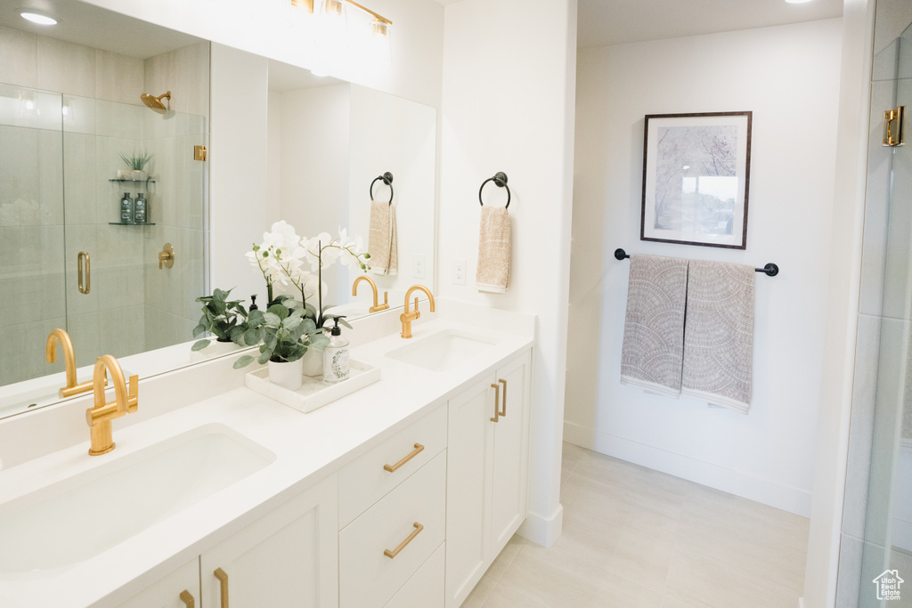 Bathroom featuring double vanity, a stall shower, and baseboards