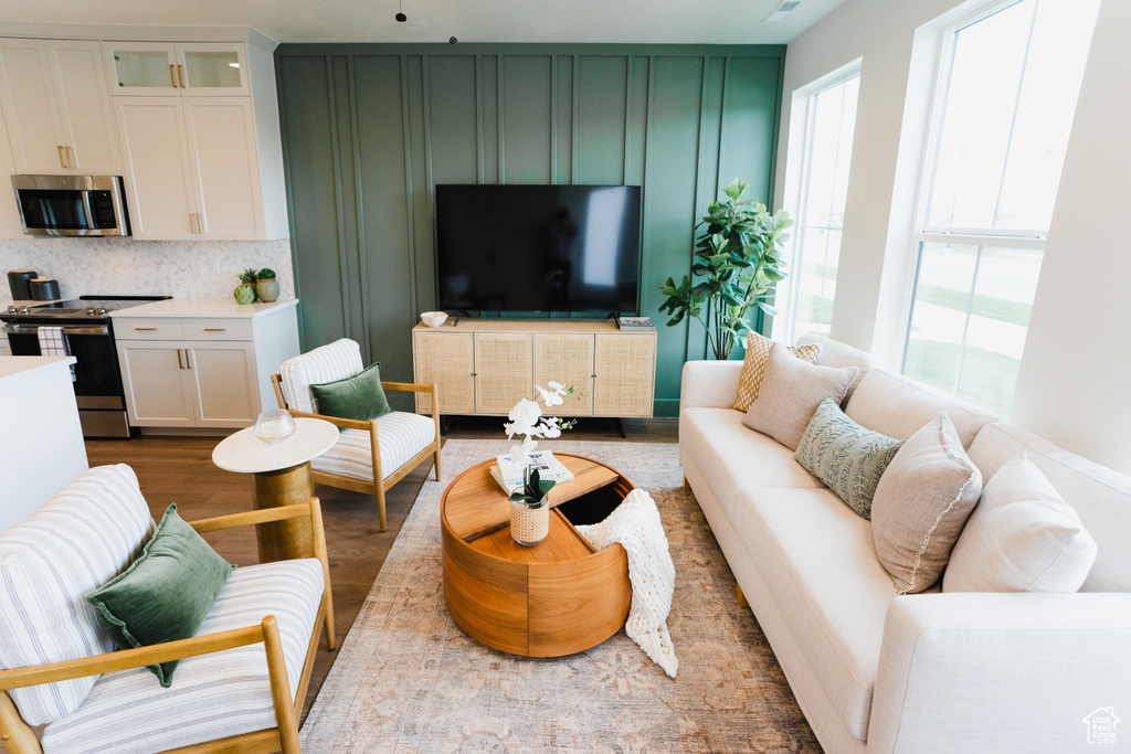 Living area with healthy amount of natural light, wood finished floors, and a decorative wall
