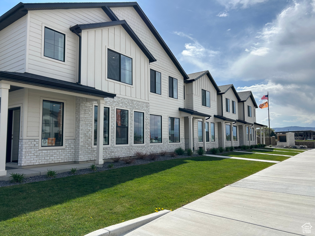 View of front facade with board and batten siding, a front lawn, and a residential view