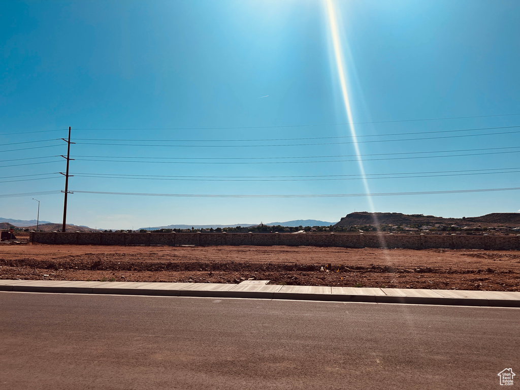 View of asphalt road featuring a mountain view and curbs