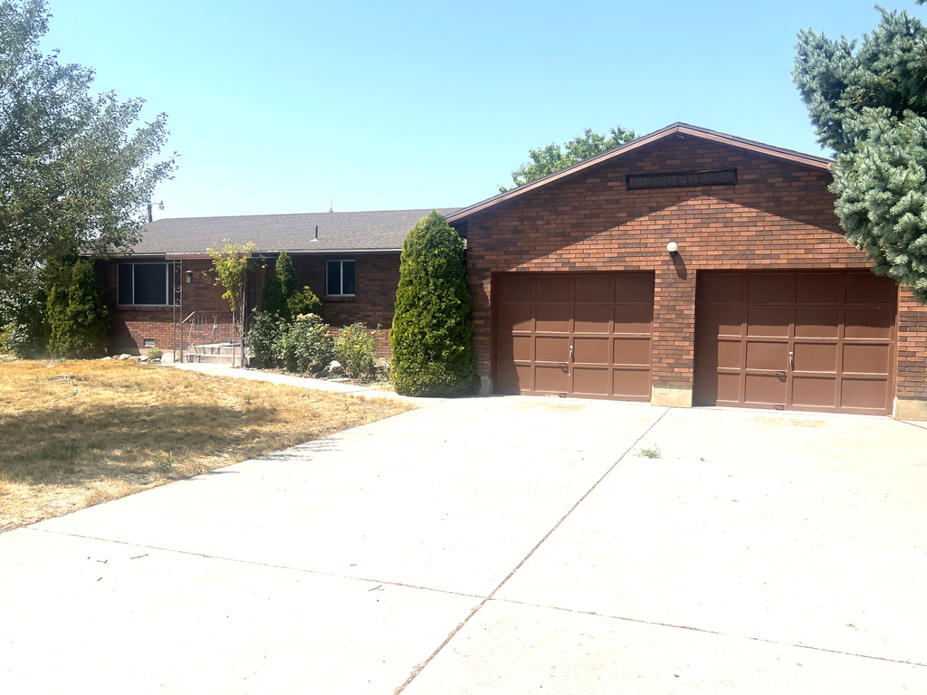 Ranch-style home featuring brick siding, a garage, and driveway