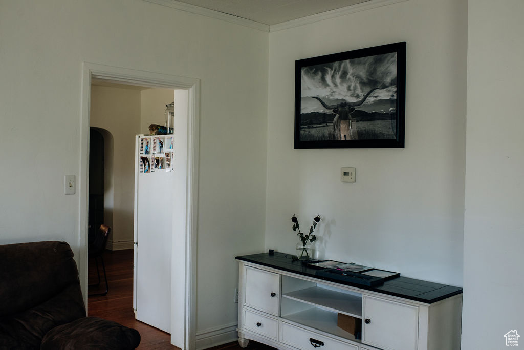 Hallway with arched walkways, dark wood-style floors, and crown molding