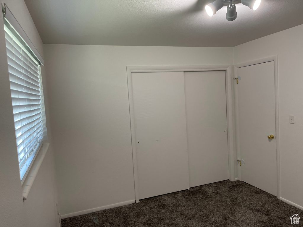 Unfurnished bedroom featuring dark carpet and a closet