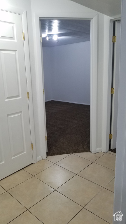 Hallway featuring light colored carpet, light tile patterned floors, and baseboards