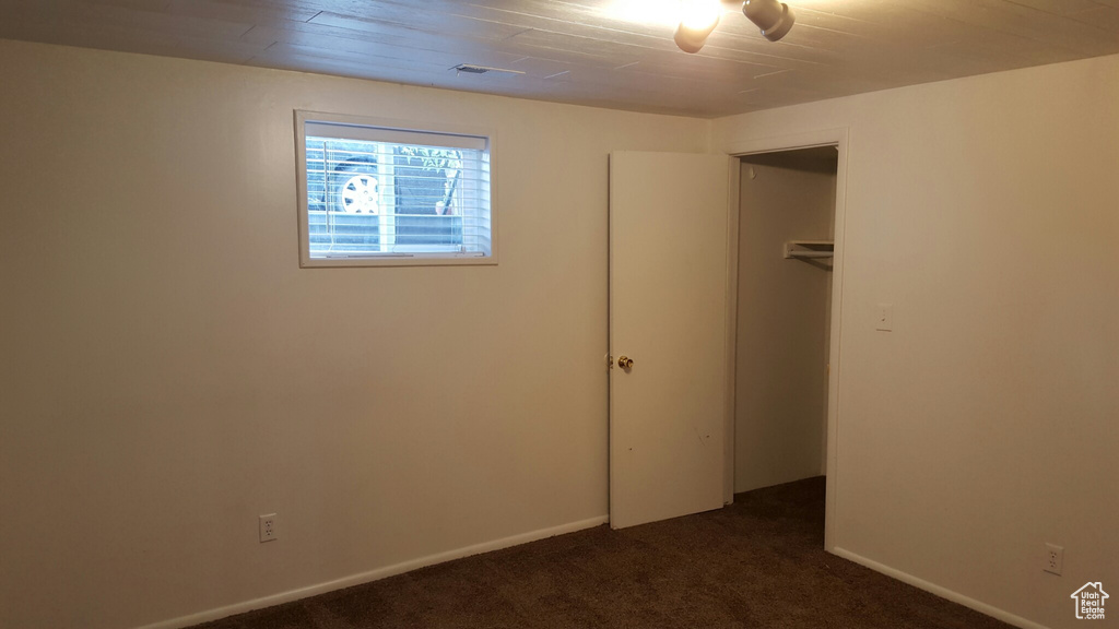 Unfurnished bedroom with dark carpet, a closet, and baseboards