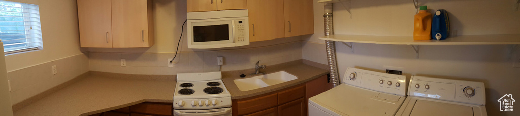 Kitchen with white appliances, washing machine and clothes dryer, a sink, and plenty of natural light