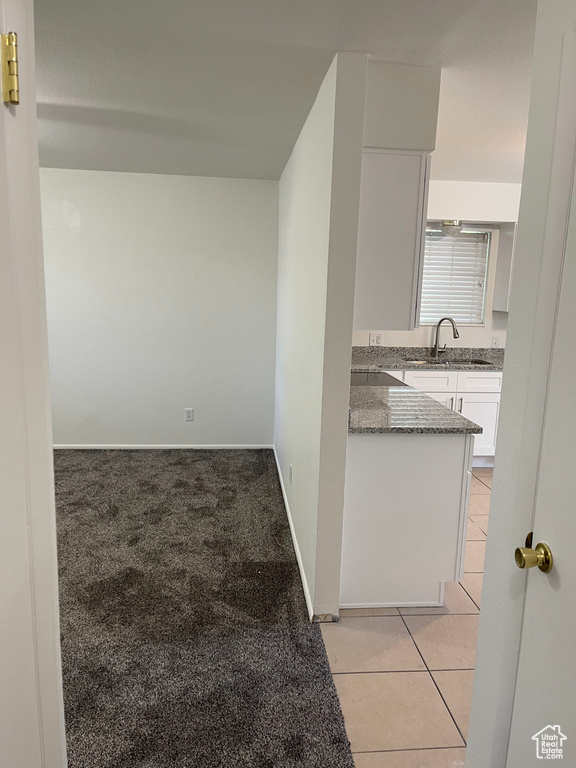 Hall featuring a sink, light tile patterned floors, baseboards, and light colored carpet
