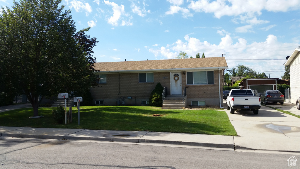 View of front of home with brick siding, a front lawn, and driveway