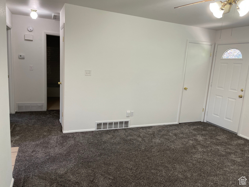 Entryway with dark carpet, ceiling fan, and baseboards