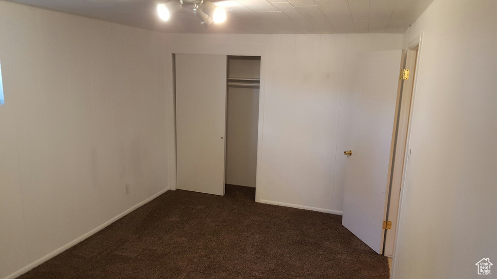 Unfurnished bedroom with dark carpet and a closet
