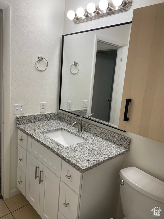 Half bathroom featuring vanity, toilet, and tile patterned floors