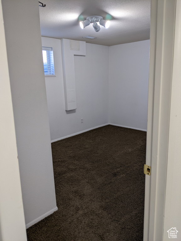 Carpeted empty room featuring a textured ceiling and baseboards