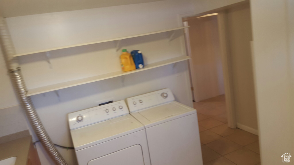Laundry room with washer and clothes dryer and light tile patterned floors