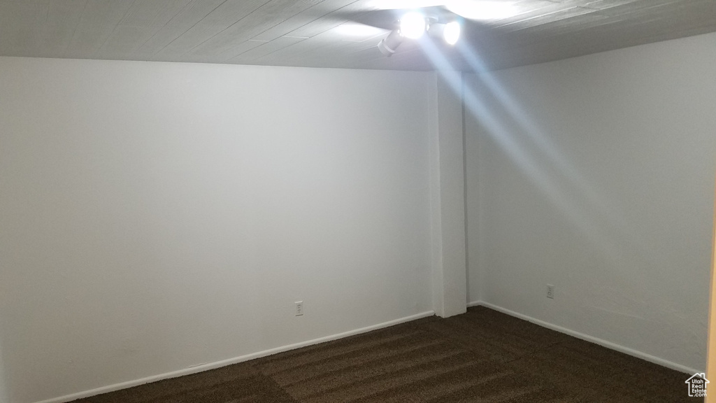 Spare room featuring dark carpet and baseboards
