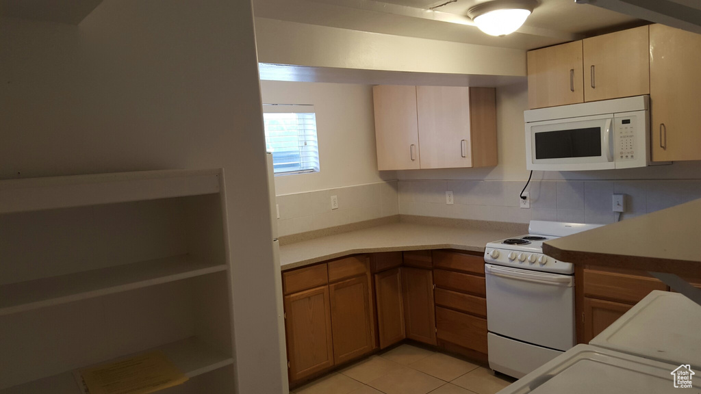Kitchen featuring white appliances, light tile patterned floors, light countertops, tasteful backsplash, and brown cabinets