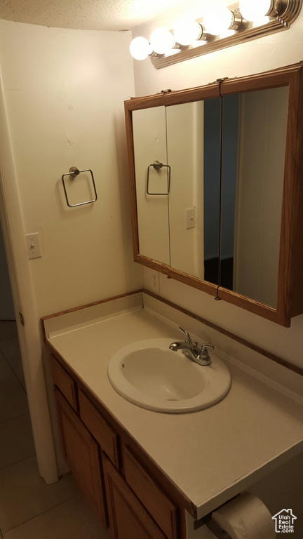 Bathroom with vanity, tile patterned flooring, and a textured ceiling