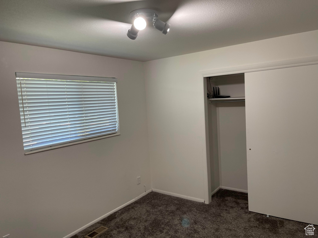 Unfurnished bedroom with carpet, a closet, ceiling fan, and baseboards
