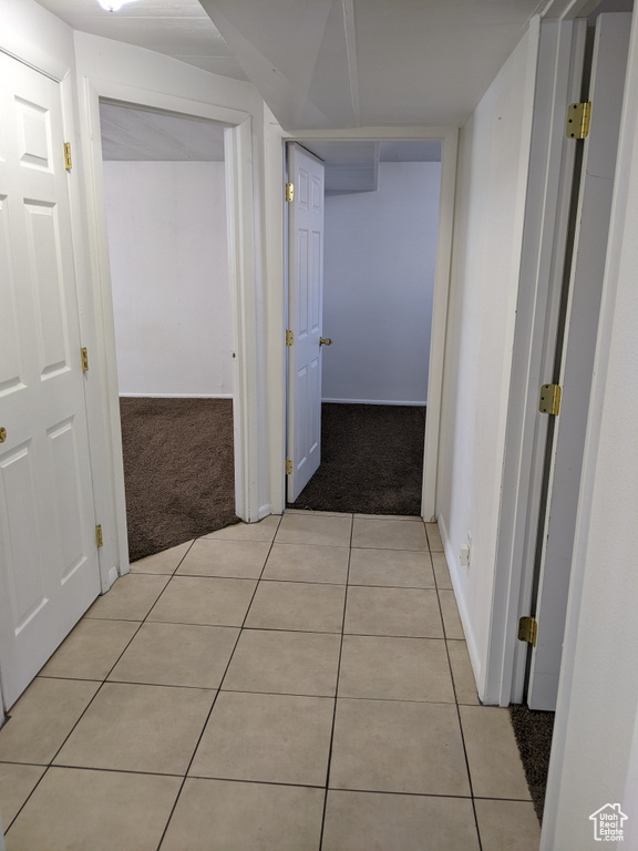 Hall with light carpet, light tile patterned flooring, and baseboards