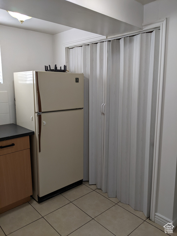 Kitchen with freestanding refrigerator, dark countertops, and light tile patterned flooring