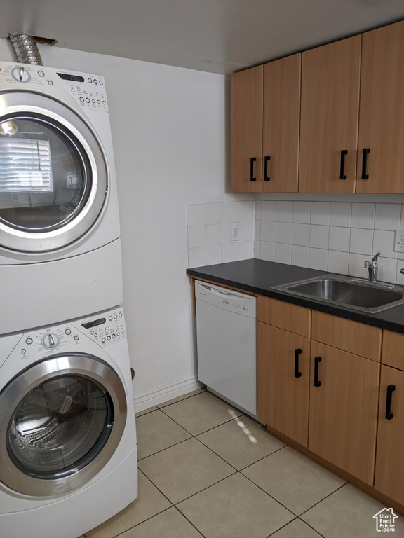Laundry area with stacked washer / dryer, light tile patterned flooring, and baseboards