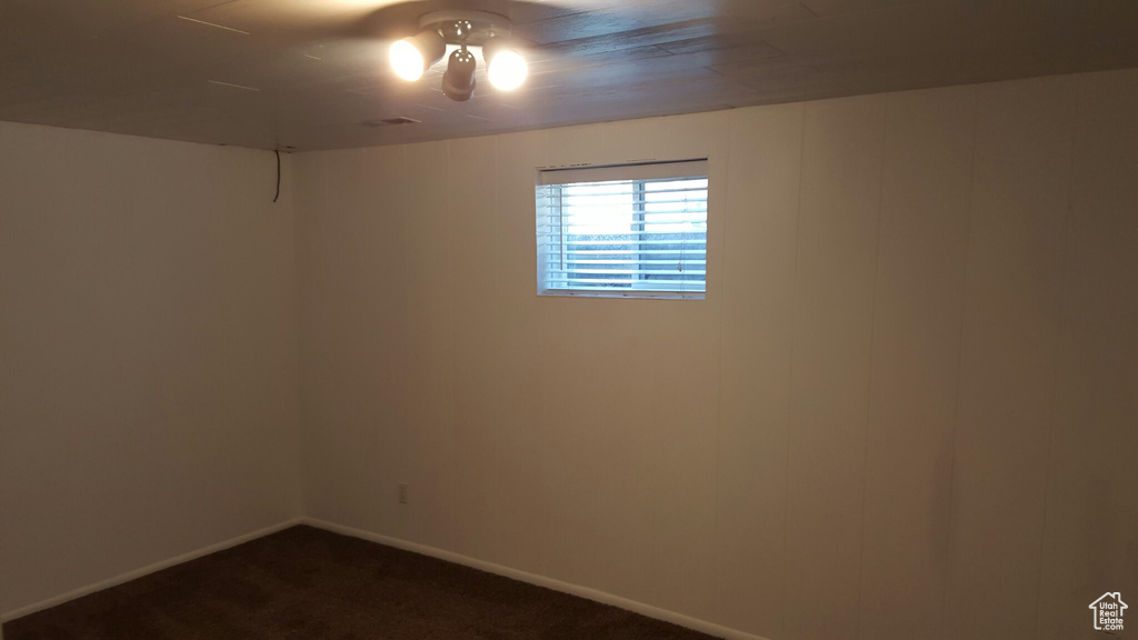 Spare room with dark carpet and baseboards