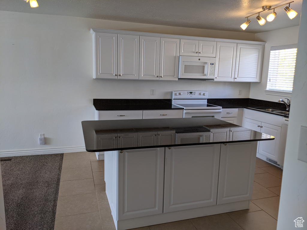 Kitchen featuring white appliances, a sink, light tile patterned flooring, and white cabinets