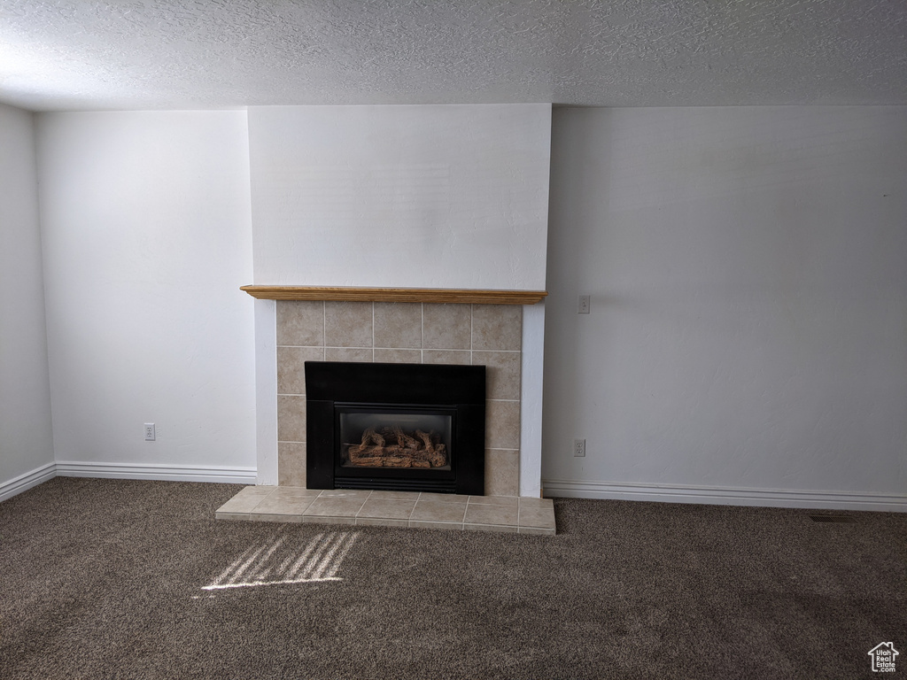 Detailed view of carpet, a fireplace, a textured ceiling, and baseboards