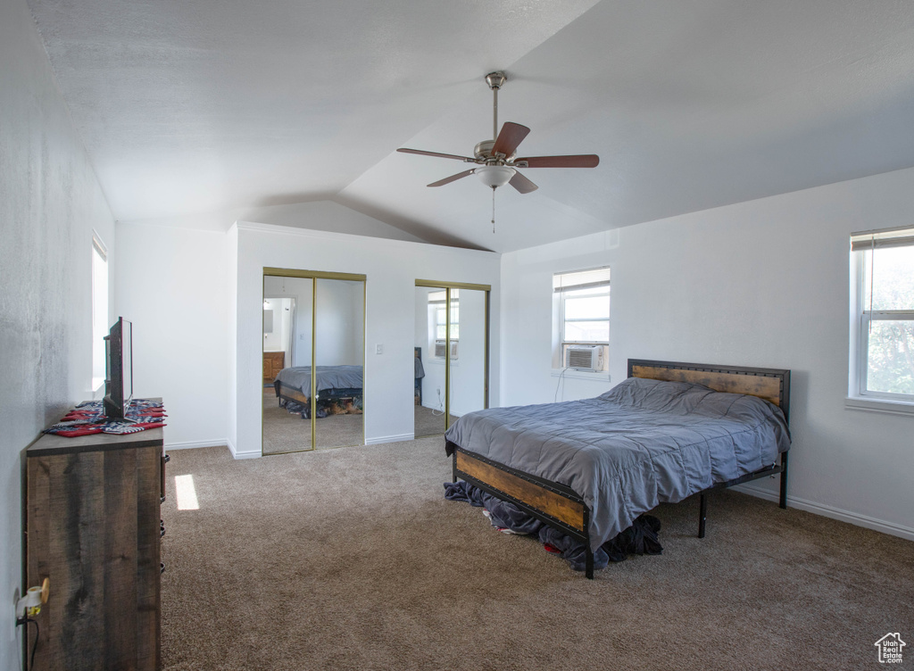 Bedroom featuring vaulted ceiling, multiple closets, carpet flooring, cooling unit, and baseboards