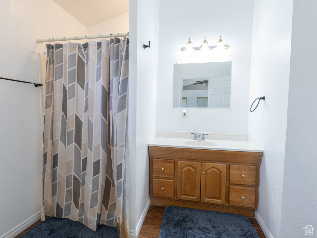 Bathroom with vanity, a shower with curtain, baseboards, and wood finished floors