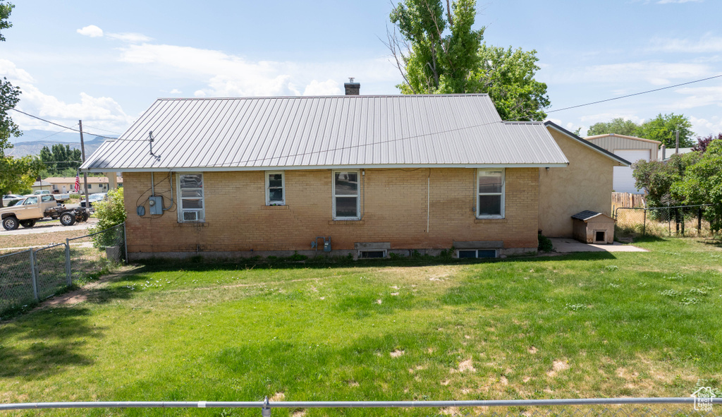 Rear view of property featuring brick siding, a chimney, and metal roof