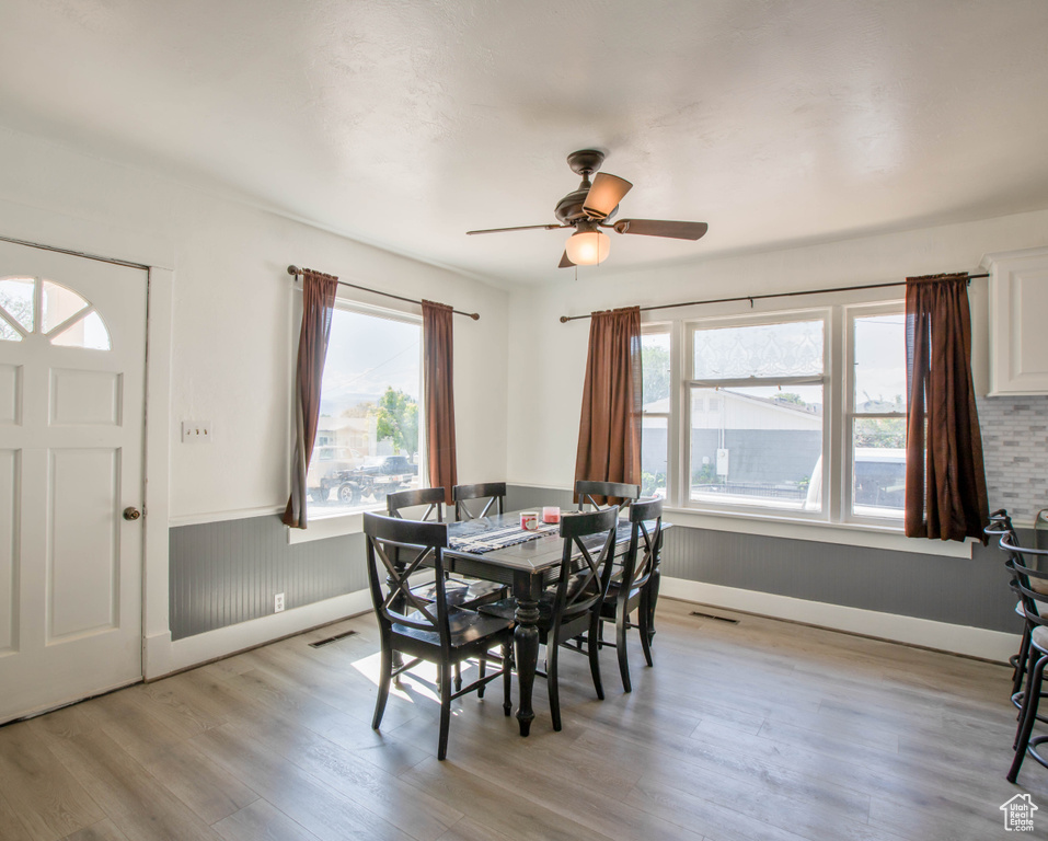 Dining room with light wood finished floors, a ceiling fan, and baseboards