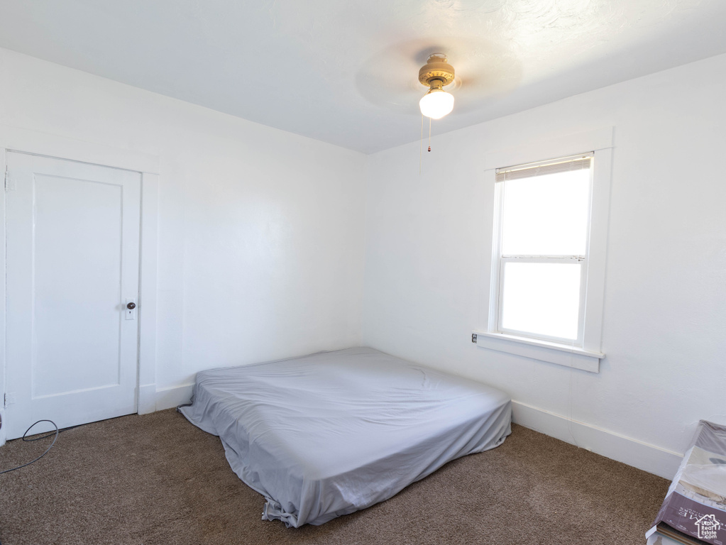 Carpeted bedroom featuring a ceiling fan