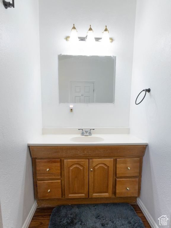 Bathroom with vanity, wood finished floors, and baseboards