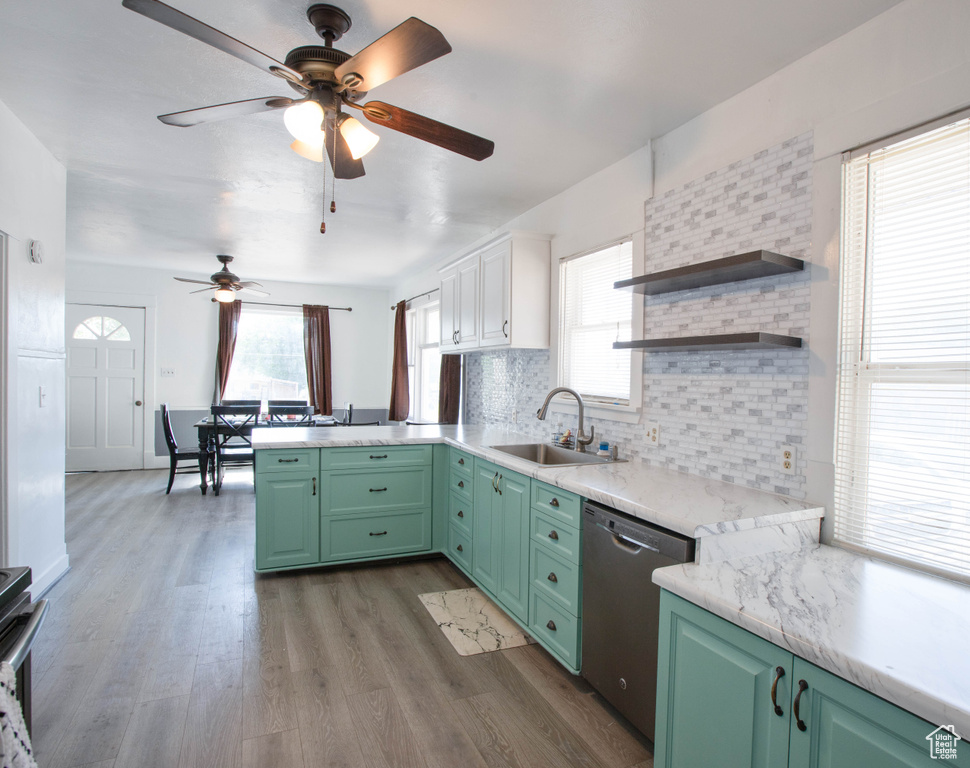 Kitchen with stainless steel dishwasher, a sink, green cabinetry, a ceiling fan, and decorative backsplash