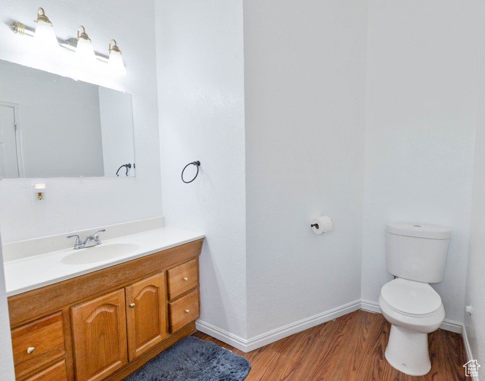 Bathroom featuring wood finished floors, toilet, vanity, and baseboards